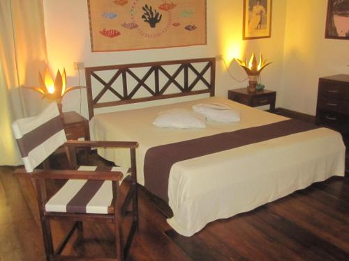 a bedroom with a large bed and two chairs at Corail Noir Hotel in Ambaro