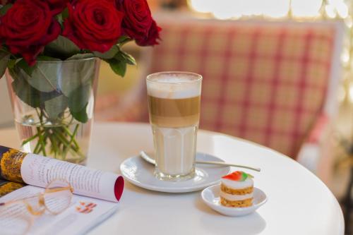 a table with a glass of milk and a vase of roses at Landhotel Restaurant zur Krone in Gottenheim