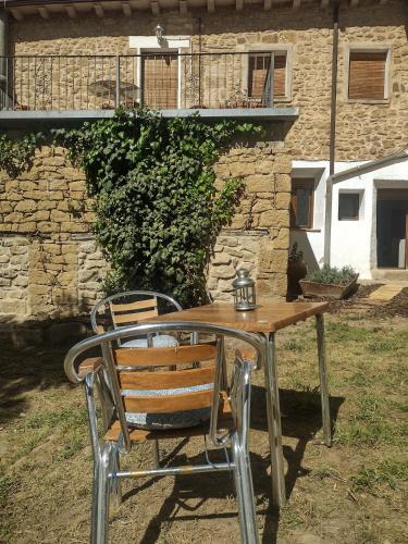 a wooden table and a chair in front of a building at El Desván del Campanero apartamento con jardín in Murillo de Gállego