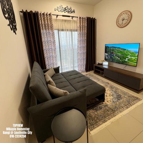 uma sala de estar com um sofá e uma televisão em TOPVIEW Mikayla Homestay Bangi @ Southville City em Kampong Tangkas