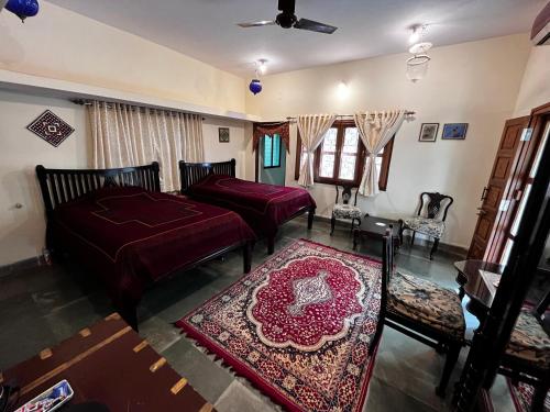 a living room with two beds and a rug at Sharad Baug homestay in Bhuj