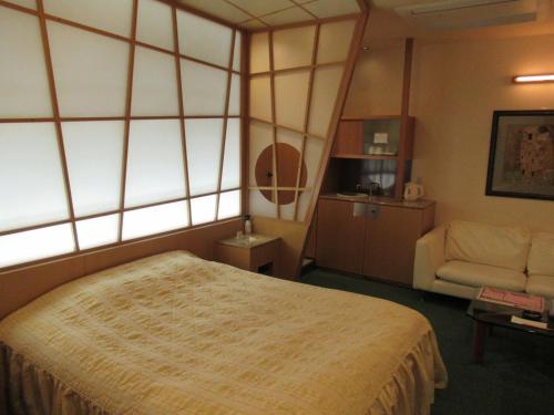 Habitación de hotel con cama y sofá en Hotel Shuyukan (Adult Only), en Izumisano