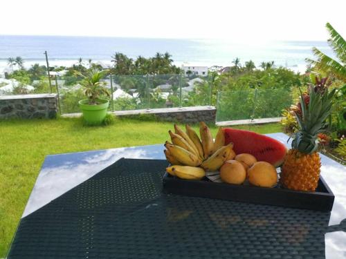 a plate of fruit on a table with a pineapple at Appart neuf classé 4*+ jardin St Gilles Bains in Grand Fond