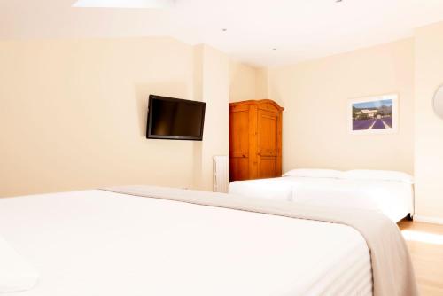 a bedroom with two beds and a flat screen tv at Hotel Sauce in Zaragoza