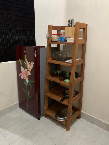 a wooden book shelf next to a refrigerator at Besakih Homestay & Villa in Besakih