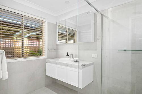 a white bathroom with a sink and a shower at The Scotty House - EV and pet friendly in Moss Vale