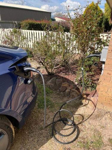 a garden hose hooked up to a car in a yard at The Scotty House - EV and pet friendly in Moss Vale