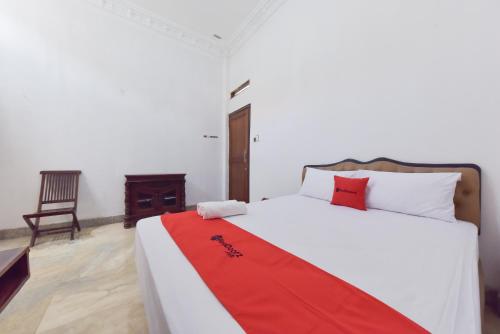 a bedroom with a bed with a red blanket on it at RedDoorz Syariah near Dago Pakar 2 in Bandung