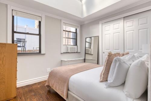 um quarto branco com uma cama grande e 2 janelas em UES 3br penthouse w gym wd nr Central Park NYC-1110 em Nova York