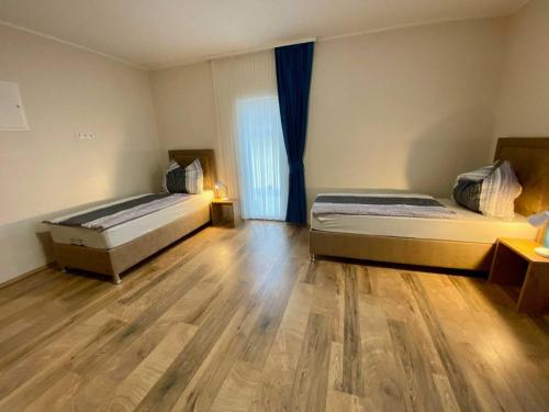 two beds in a room with a wooden floor at Pension Austria in Mitterdorf im Mürztal