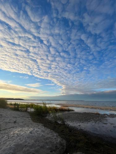 a beach with a cloudy sky and the ocean at Pärli puhkemaja / Pearl riverside house in Pudisoo