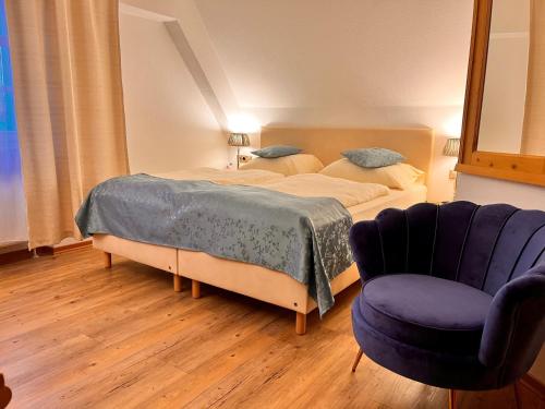 a bedroom with two beds and a blue chair at Posthotel Arnold in Gunzenhausen