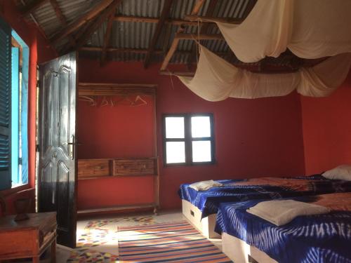 Duas camas num quarto com paredes vermelhas e janelas em Jinack Lodge em Jinack Island