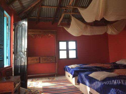 two beds in a room with red walls and windows at Jinack Lodge in Jinack Island