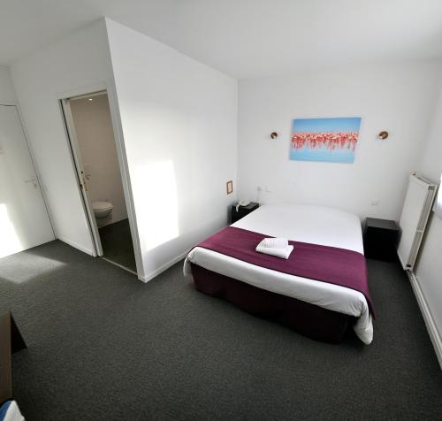a white room with a bed and a mirror at Logis hôtel restaurant la Haute Forêt in Vertou
