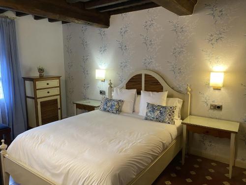 a bedroom with a bed with white sheets and blue wallpaper at Apartamentos Rurales El Zarzo in Hervás