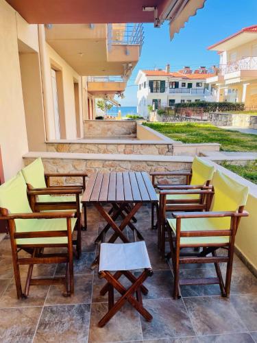 a patio with chairs and a wooden table and chairs at DARIVA apartment Nea Skioni in Nea Skioni