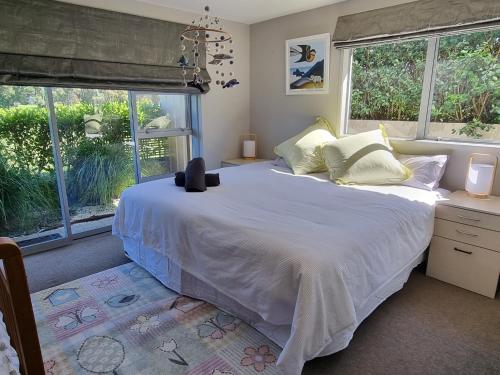 a bedroom with a large white bed with windows at The Sandy Golfer in Mount Maunganui