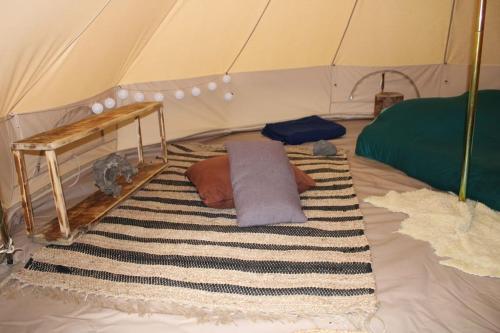 BurzetにあるTente Tipi en pleine forêtのテント付きの客室で、ベッド1台とラグが備わります。