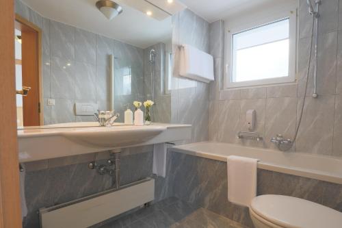 een badkamer met een wastafel, een toilet en een bad bij Hotel Alpin Superior in Saas-Fee