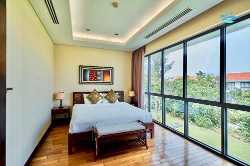 a bedroom with a bed and large windows at Emblem Sea 2 bedroom villas in Da Nang