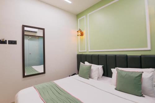 a bedroom with a bed with green and white pillows at The Cattleya Hotel, Near Mumbai International Airport in Mumbai