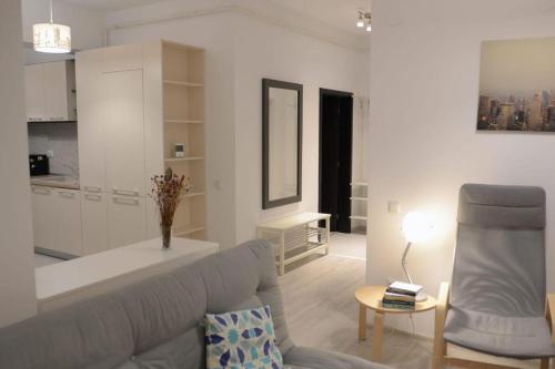 a white living room with a couch and a chair at Urban Accommodation - Palas Mall Iasi in Iaşi