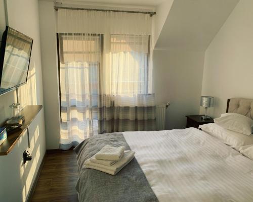 a white bedroom with a bed and a window at Art of Harmony in Piatra Neamţ