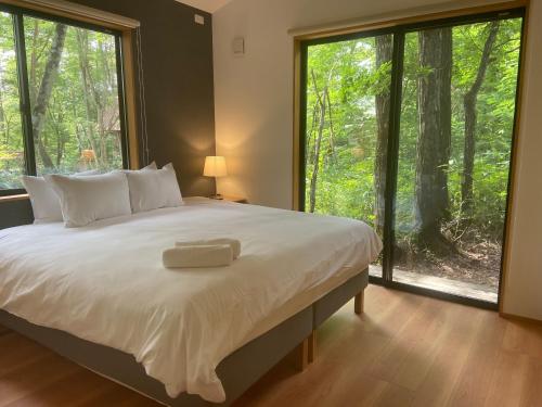 a bedroom with a large bed and large windows at Akamatsu House in Hakuba
