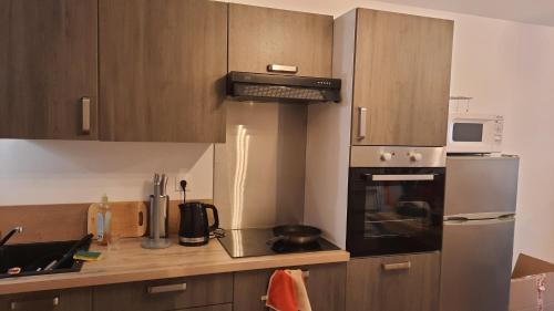 a kitchen with wooden cabinets and a stove top oven at Appartement neuf et cosy 2 à 6 personnes tout équipé in Allevard
