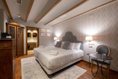 a bedroom with a large white bed and a table at Hotel Cetina Palacio de los Salcedo in Baeza