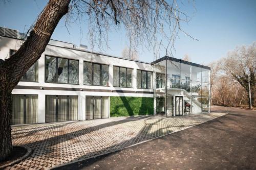 un gran edificio blanco con un árbol delante en Birdies Rendezvényház Apartmanok, en Szentendre