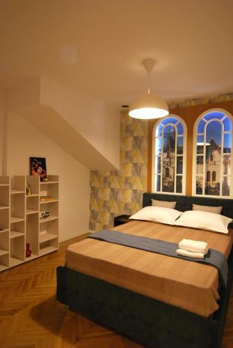 a bedroom with a large bed and two windows at Heritage Apartment at Berindey French Villa, City Center, Bucharest in Bucharest
