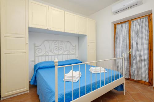 um quarto com uma cama azul e armários brancos em San Paolo House em Porto San Paolo