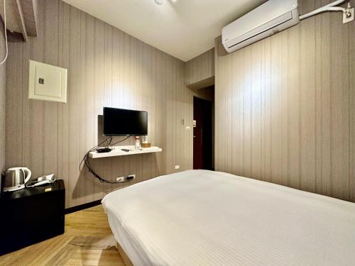 a bedroom with a bed and a flat screen tv at 澄居 live in in Taichung