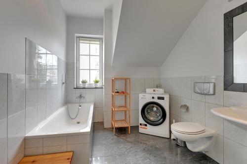 a bathroom with a tub and a toilet and a washing machine at Villa Walecznych in Zaspa