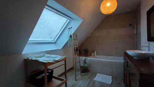 La salle de bains est pourvue d'une fenêtre, d'un lavabo et d'une baignoire. dans l'établissement Maison récente tout confort a proximité de la plage, à Pornichet
