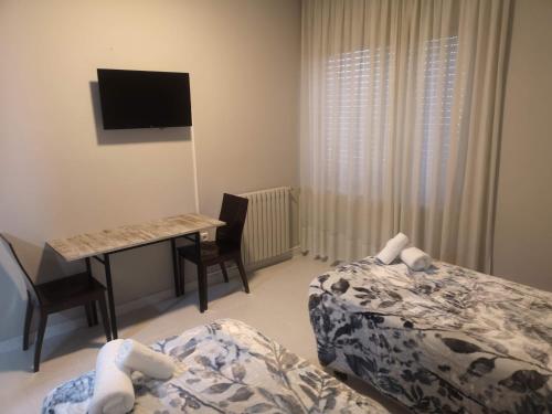 1 dormitorio con 2 camas y escritorio con ordenador en Hostal Conde de Lemos en Ponferrada
