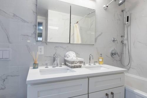 ein weißes Badezimmer mit einem Waschbecken und einem Spiegel in der Unterkunft Elegant East Side in New York