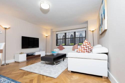 ein Wohnzimmer mit einem weißen Sofa und einem TV in der Unterkunft Elegant East Side in New York