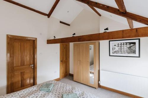 a bedroom with a bed and a wooden door at ELM HOUSE BARN - Converted One Bed Barn at the gateway to the Lake District National Park in High Hesket