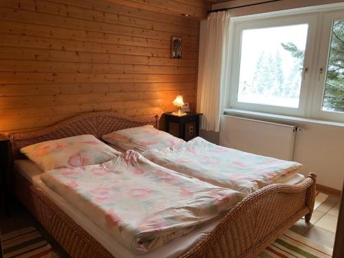 wiklinowe łóżko w pokoju z oknem w obiekcie Ferienwohnung Schwarzwaldglueck w mieście Feldberg