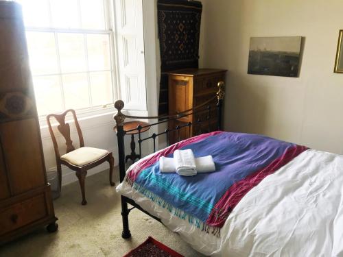 a bedroom with a bed and a chair and a window at Grand top floor apartment in the Royal Bank House in Maybole