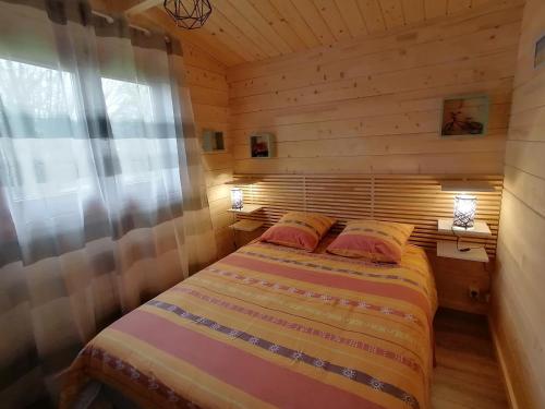 1 dormitorio con 1 cama en una cabaña de madera en Chalet "L'aventure" calme et verdoyant - 6 pers, en Sulniac