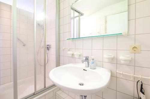a white bathroom with a sink and a shower at Appartement Greenlön in Westerland