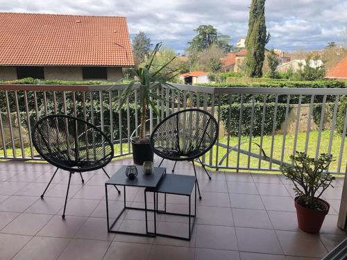 two chairs and a table on a balcony at Studio Moderne, Terrasse et Parking in Romans-sur-Isère