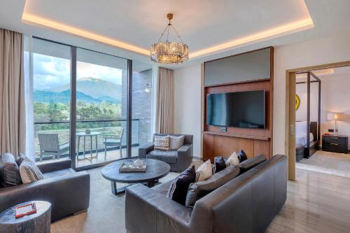 a living room with a couch and a tv and a table at Gran Melia Arusha in Arusha