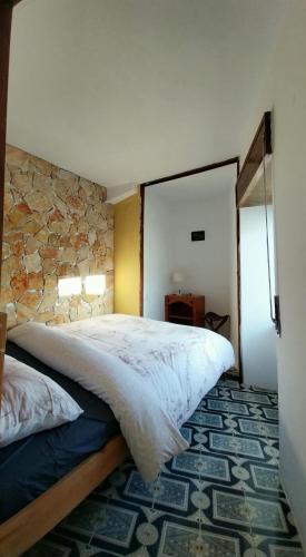 a bedroom with a large bed and a stone wall at Casa Maritima in Aljezur