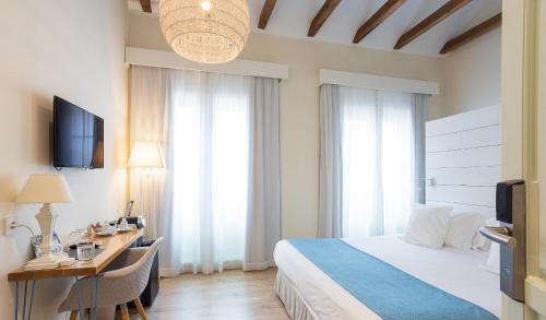 a hotel room with a bed and a desk and a television at Madeinterranea Suites in Málaga