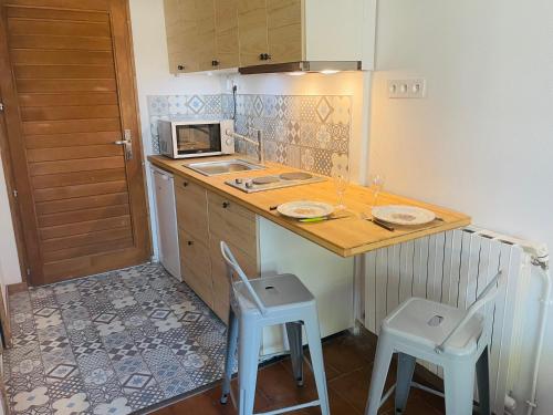 une petite cuisine avec un comptoir et deux tabourets dans l'établissement gite Marydidou, à Entressen